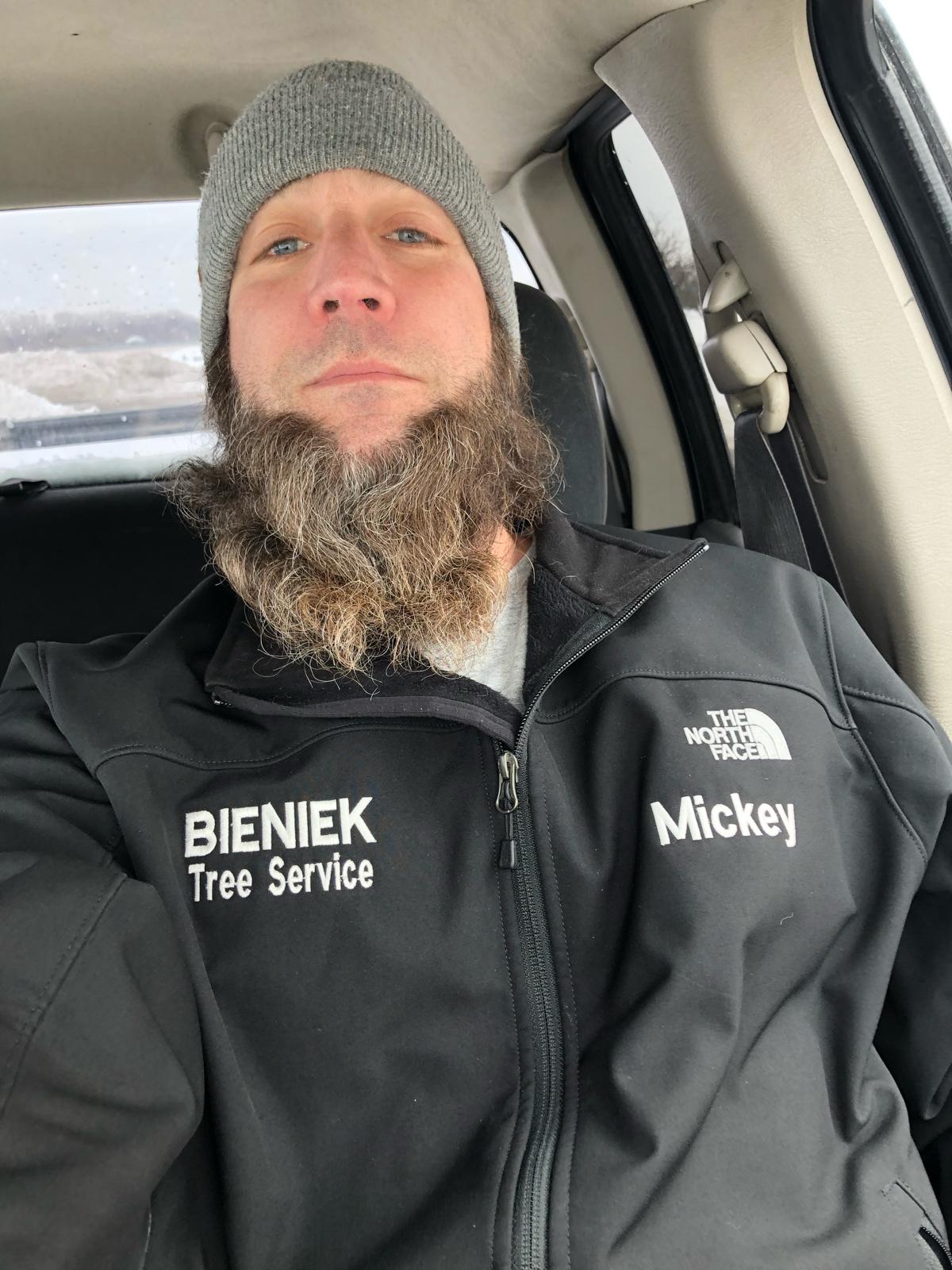 Mickey, certified arborist, wearing a Bieniek Tree Service jacket in a vehicle, representing the tree care team's professionalism and expertise.